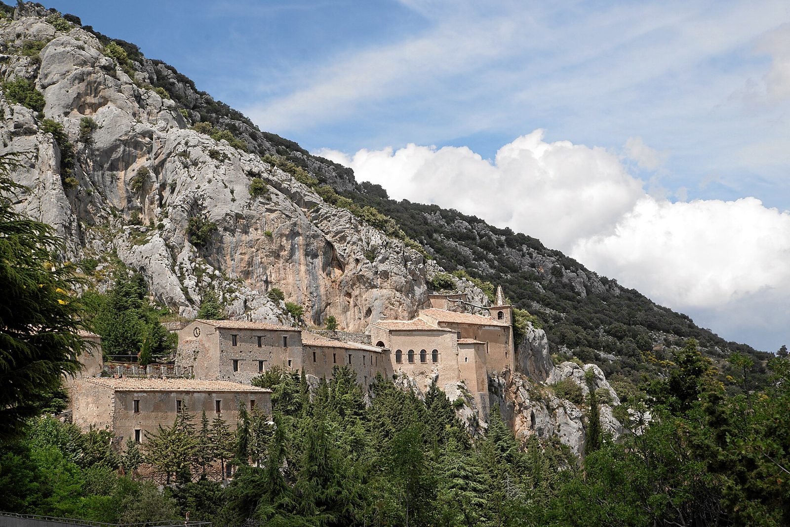 Il Santuario della Madonna delle Armi, complesso di edifici in pietra con campanile addossato alla parete rocciosa del Monte Sellaro, circondato da boschi sopra Cerchiara di Calabria