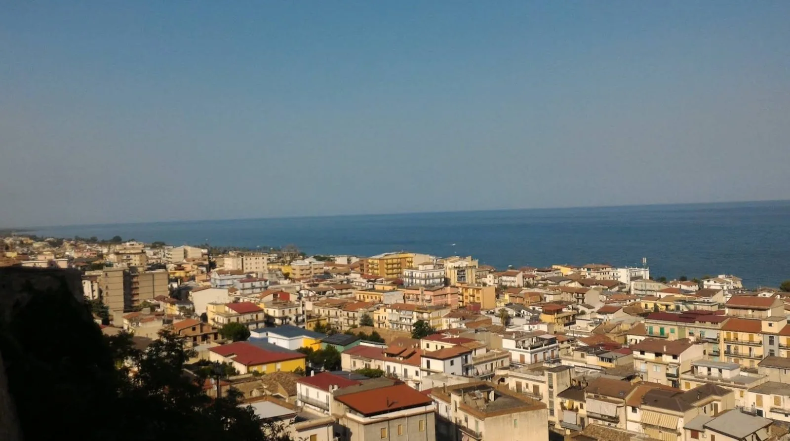 Veduta dall'alto di Trebisacce: i tetti e le case del paese digradano verso il mare Ionio sotto un cielo sereno