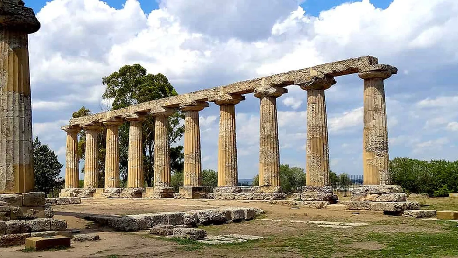 Colonne doriche di un antico tempio della Magna Grecia sotto un cielo con nuvole